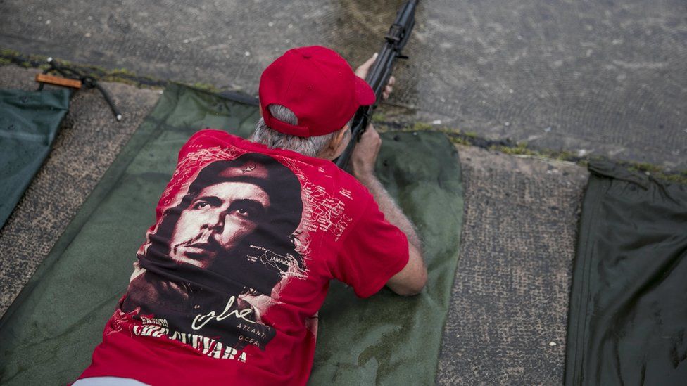 Мужчина в майке с портретом Че Гевары и ружьем в руках