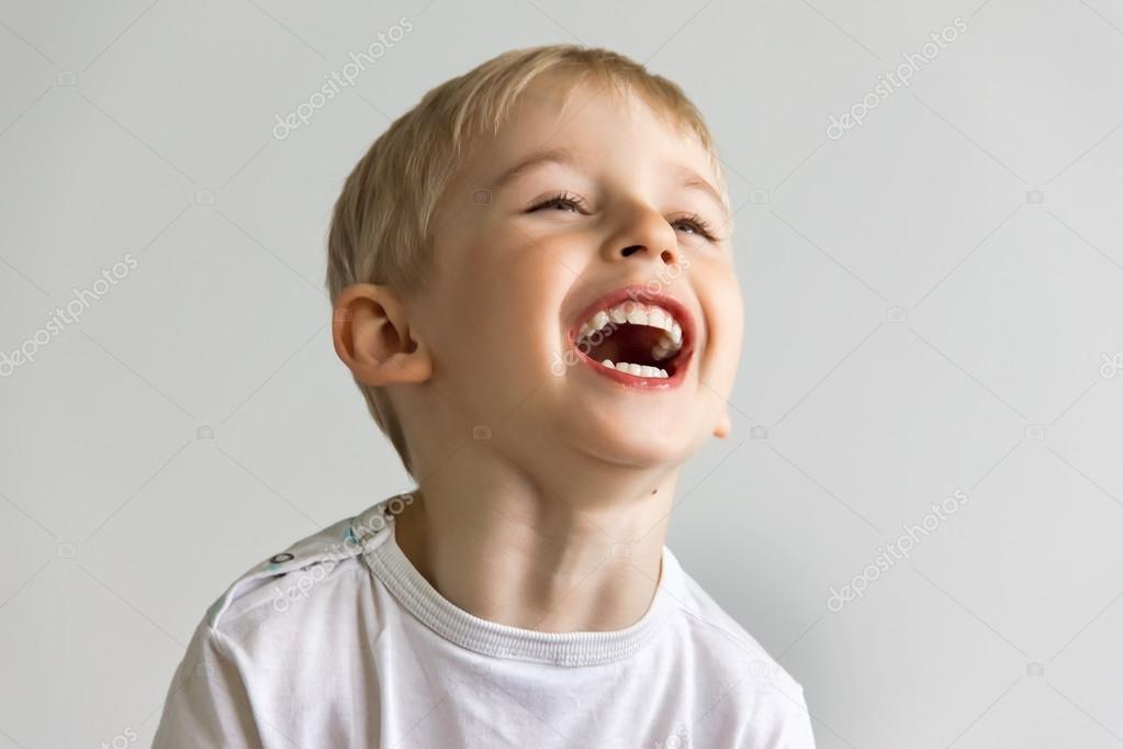 Веселый мальчик смеется, показывая белые зубы, очень мягкий фокус ...