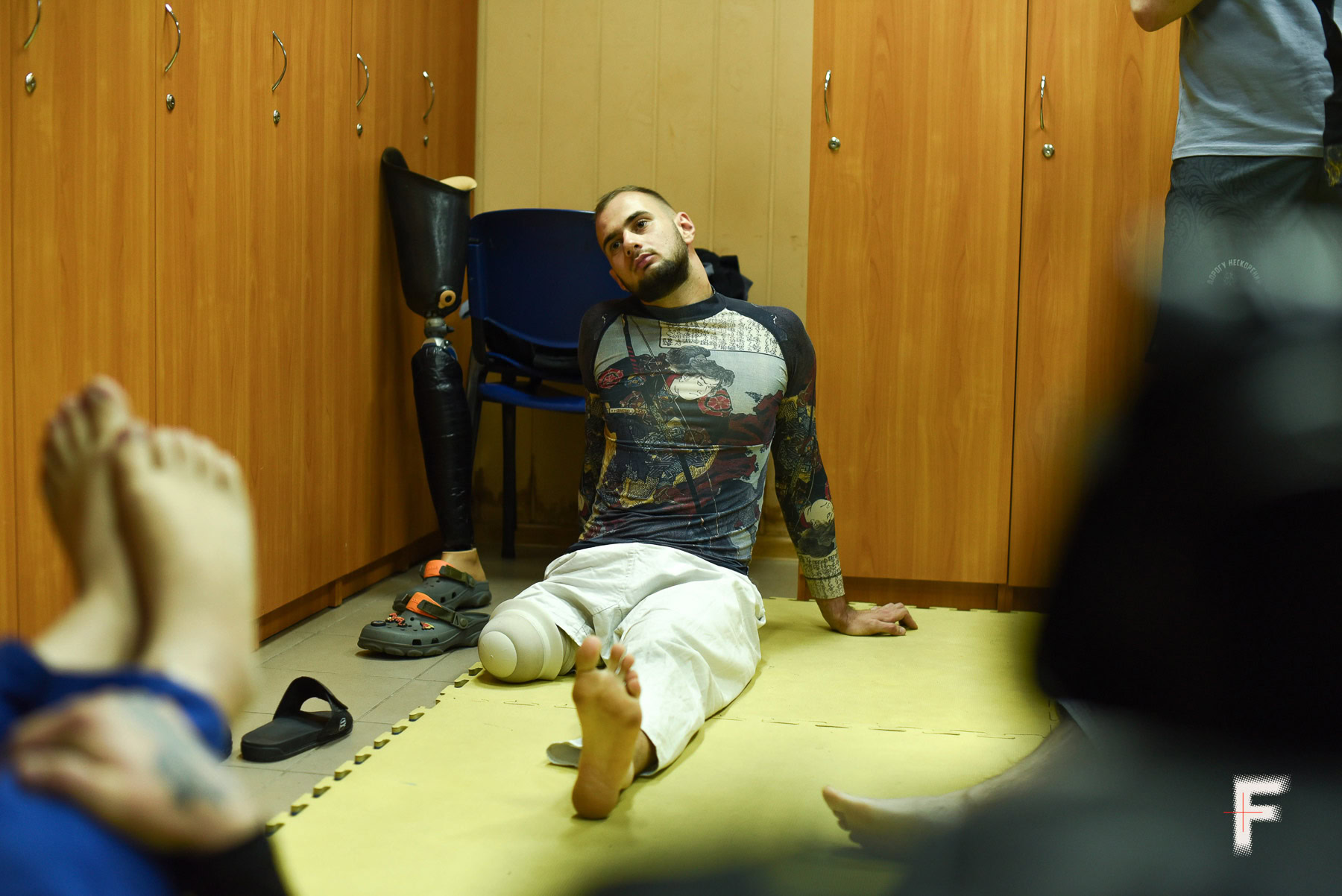 Ветеран з ампутованою ногою сидить на підлозі під час спортивного тренування з реабілітації.
