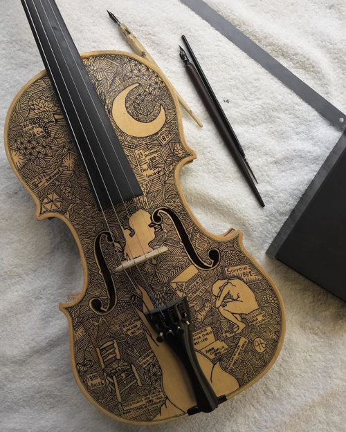Художник вручную расписывает скрипки и виолончели
