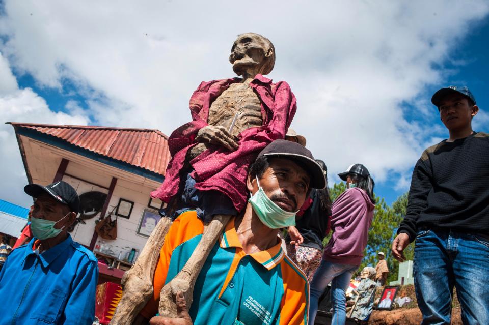 Туристы позируют на индонезийском фестивале мертвых родных