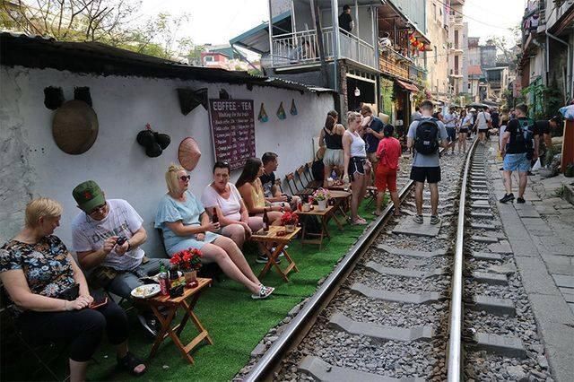 Кафе возле железной дороги, посетители которого отдыхают на рельсах
