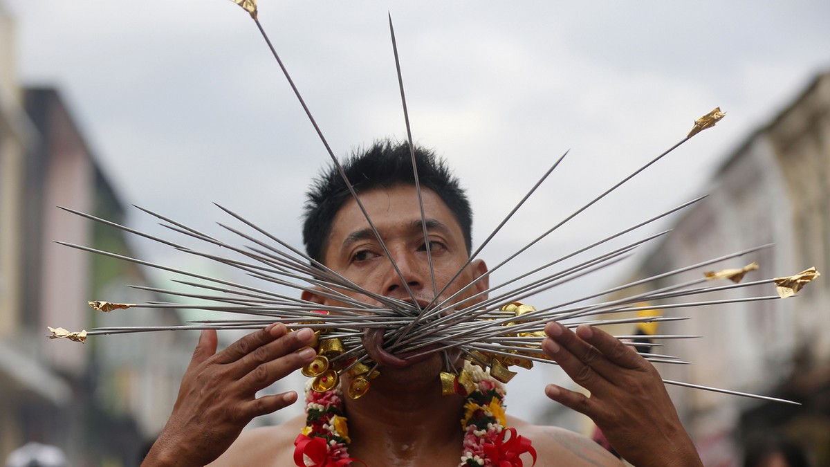 Верующие пронзают щеки на фестивале вегетарианцев в Таиланде